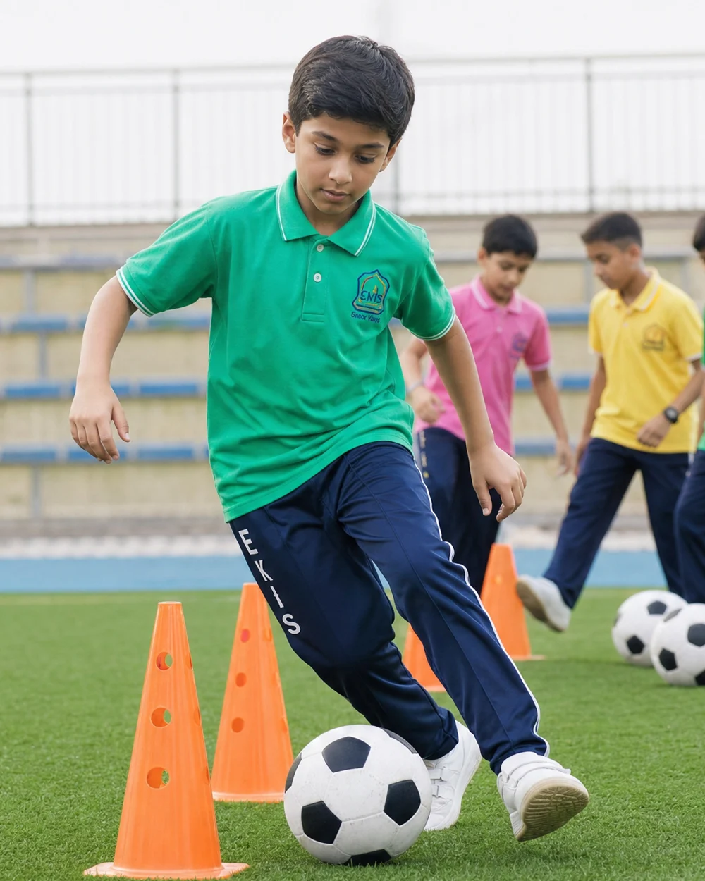 A student in EKIS sports kit controlling a football beside training cones