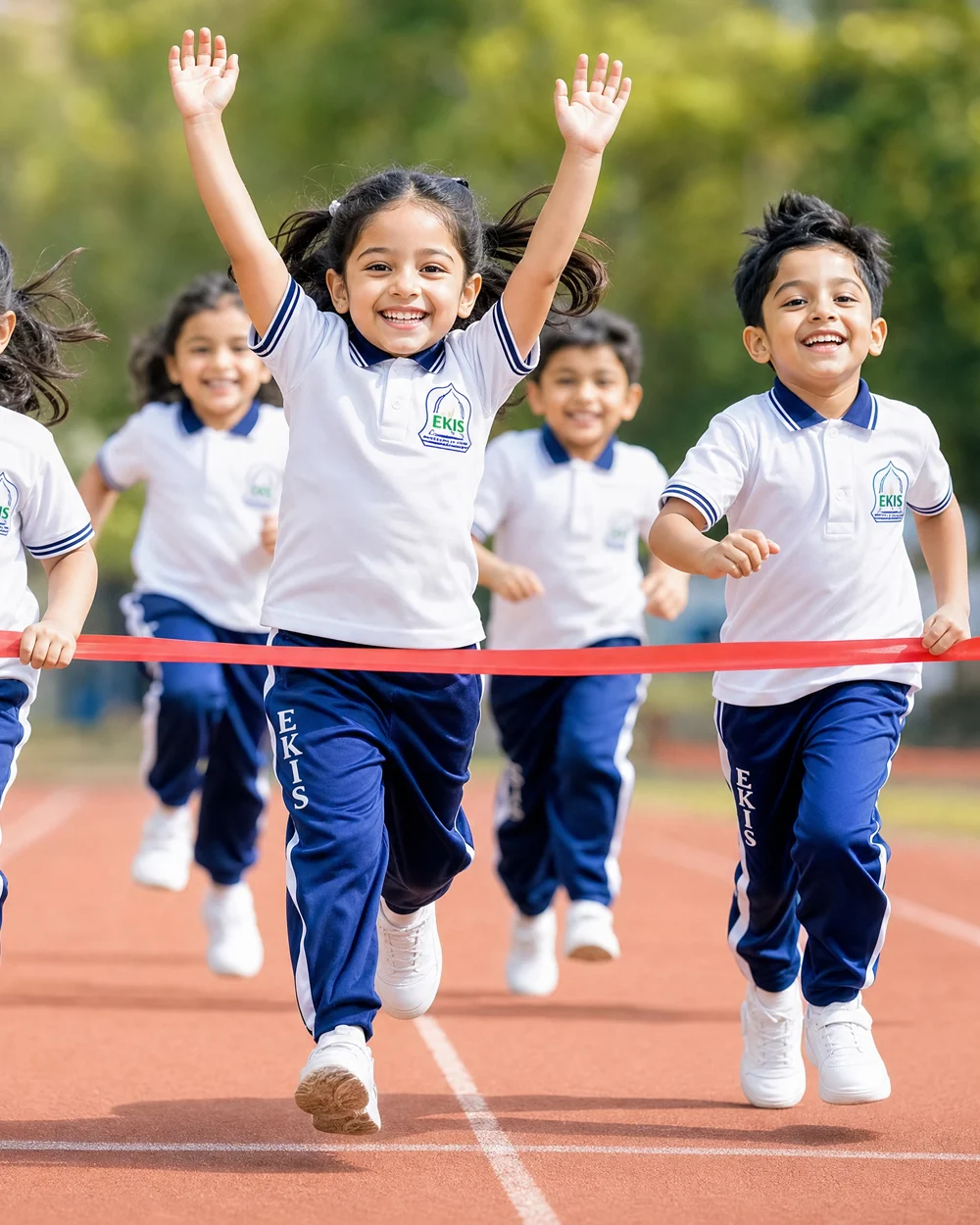 Young children in EKIS sports kit running towards a finish-line ribbon