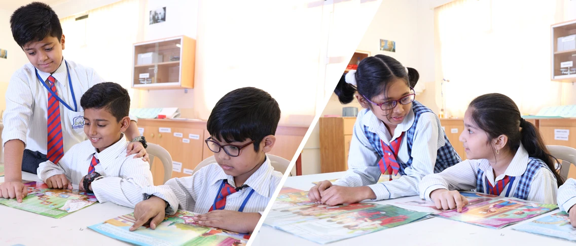 Primary-age children in school uniform reading illustrated workbooks together at classroom tables